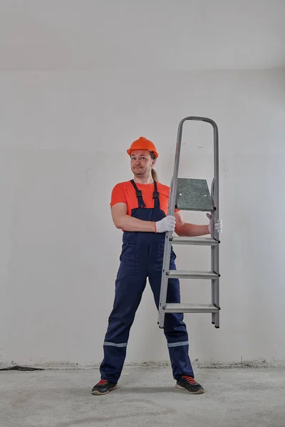 Um homem satisfeito em um capacete olha através da escada — Fotografia de Stock