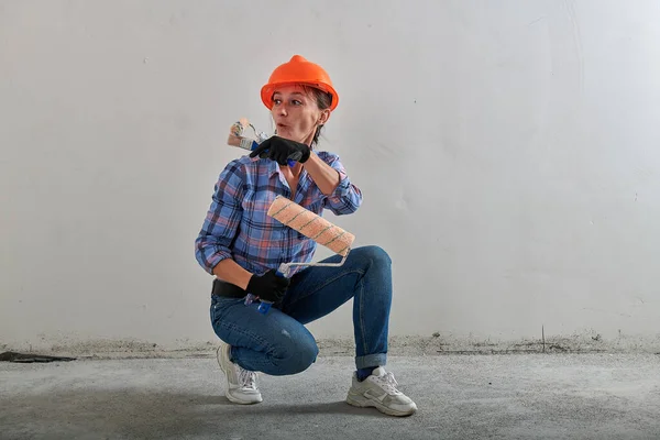 Chapéu duro laranja brilhante em uma reparadora em jeans — Fotografia de Stock
