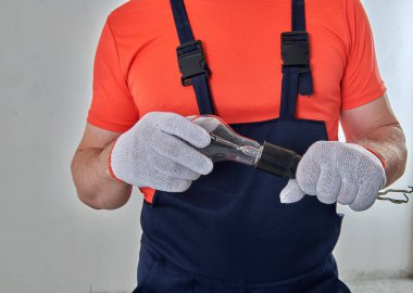 Bir elektrikçi bir ampulü prize vidalıyor.