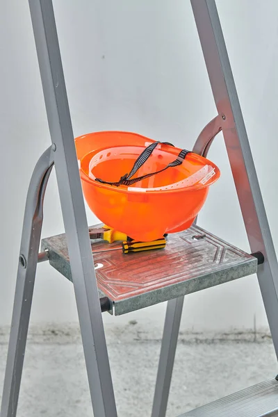 Оранжевый строительный шлем лежит на лестнице — стоковое фото