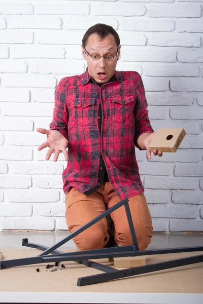 Junger Mann beim Zusammenbauen von Möbeln verwirrt — Stockfoto