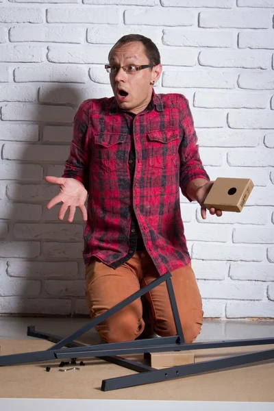 Young man confused about assembling furniture — Stock Photo, Image