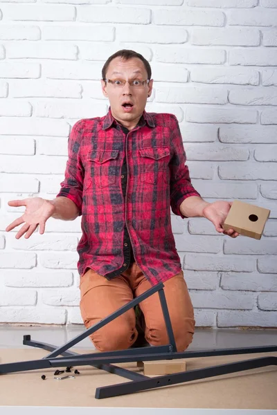 Young man confused about assembling furniture — Stock Photo, Image
