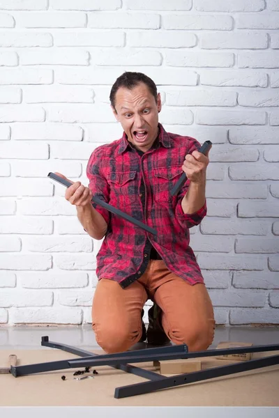 Junger Mann beim Zusammenbauen von Möbeln verwirrt — Stockfoto