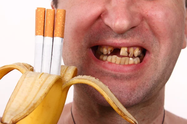 Cigarros em uma banana, fumante, dentes ruins — Fotografia de Stock