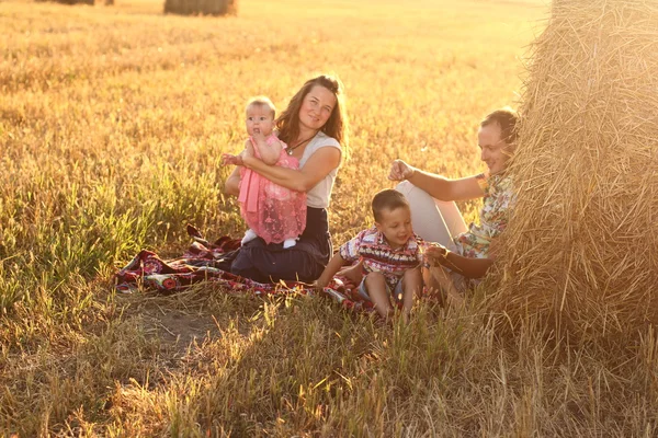 Família feliz no campo de trigo no pôr-do-sol dia ensolarado — Fotografia de Stock