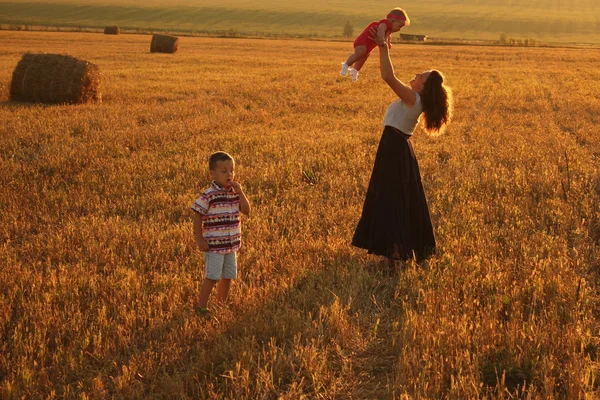 Mãe segurando bebê sorrindo em um campo de trigo — Fotografia de Stock