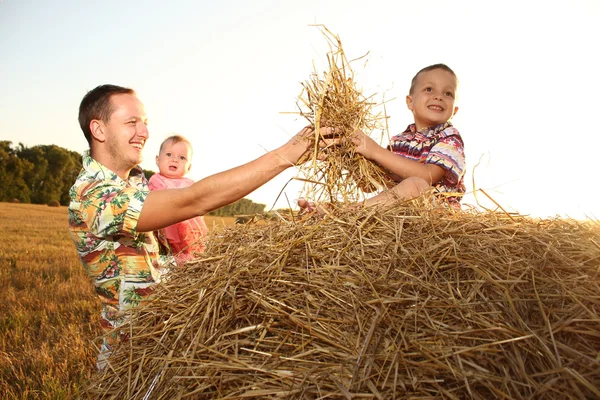 Glückliche Familie im Weizenfeld bei sonnigem Sonnenuntergang lizenzfreie Stockbilder