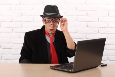 Shocked young business man using laptop looking at computer screen blown away in stupor sitting outside corporate office. Human face expression, emotion, feeling, perception, body language, reaction