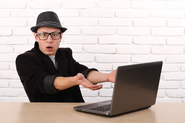 Shocked young business man using laptop looking at computer screen blown away in stupor sitting outside corporate office. Human face expression, emotion, feeling, perception, body language, reaction