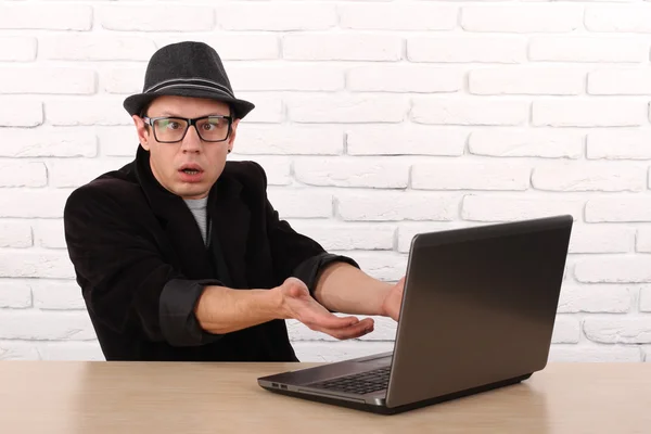 Schockierter junger Geschäftsmann, der mit seinem Laptop auf den Computerbildschirm blickt und fassungslos vor dem Büro des Unternehmens sitzt. Gesichtsausdruck, Emotion, Gefühl, Wahrnehmung, Körpersprache, Reaktion lizenzfreie Stockfotos