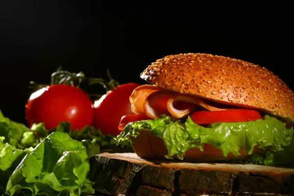 Sanduíche e tomate em mesa de madeira — Fotografia de Stock