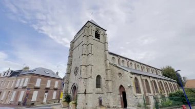 Le Crotoy, Somme Körfezi, Fransa 'daki tarihi Saint-Pierre Kilisesi, Romanesk tarzı taş maskaralığı, kemerli camları ve kare çan kulesi ile kıyı köyü merkezinde parçalı bulutlu bir gökyüzünün altında