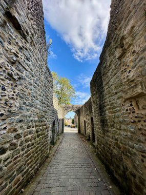 Saint-Valery-sur-Somme, Fransa - 17 Ekim 2024: Jean de Bailleul sokağı ortaçağ Guillaume kapısından geçen, kemerli geçidi ve mavi gökyüzü altında kaldırım taşları olan çakmaktaşı ve kireç taşı surları