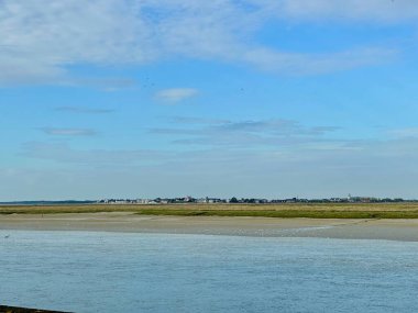 Le Crotoy Somme Körfezi 'nin karşısında, alçak sularda, gelgit düzlüklerine dağılmış sayısız siyah başlı martılar ve Cap Hornu yakınlarındaki mavi kanallar, engin açık gökyüzü ve yumuşak akşam ışığı kıyı manzarası biçiminde