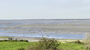 Cap Hornu, Saint-Valery-sur-Somme 'dan gelen alçak gelgitte Somme Körfezi boyunca panoramik manzara, dalgalı gelgit kanallarını, geniş kumsalları, işaret şamandıralarını, deniz kuşlarını ve yemyeşil otlakları gösteriyor sonbahar gökyüzünün altında