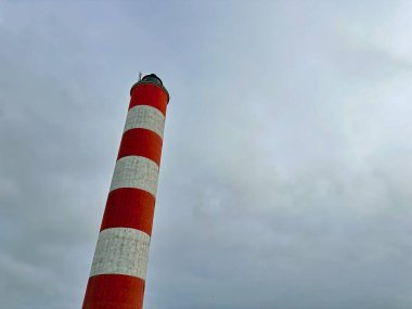 Berck-sur-Mer deniz feneri, kıyı kum tepeleri ve koruyucular üzerinde yükselen kırmızı ve beyaz çizgili deniz feneri, Pas-de-Calais, kuzey Fransa 'daki ikonik deniz manzaralı gökyüzü bulutlu