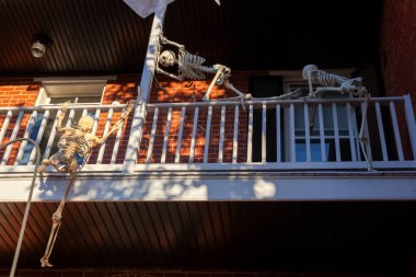Frederick, MD, ABD 10 / 13 / 2020: Bir evin ikinci katındaki cadılar bayramı balkonunda çok yaratıcı bir dekorasyon. Korkunç iskeletler kırılıp eve girmek için tırmanıyor. Gerçekçi bir cadılar bayramı teması.