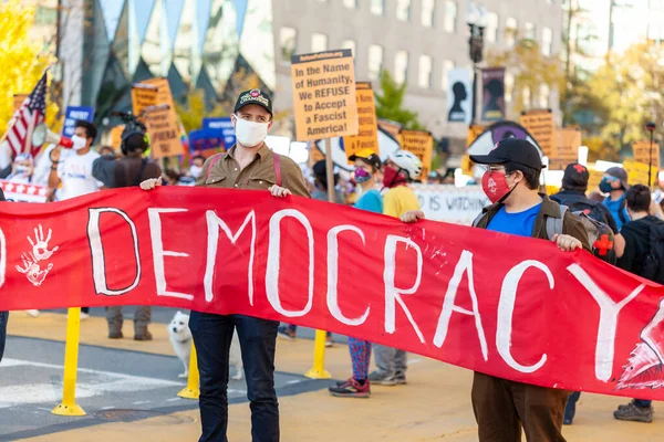 Washington DC, ABD 11 / 06 / 2020: Gül tokalaşması maskesi takan bir grup demokratik sosyalist, ABD seçimlerinde Donald Trump 'ın yenilgisini kutlamak için Beyaz Saray yakınlarında yürüyüş yapıyor.