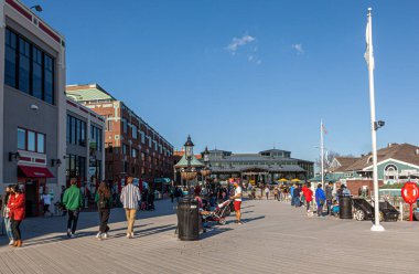 Alexandria, VA, ABD 11-29-2020: Tarihi İskenderiye 'nin liman bölgesinde Potomac nehri kıyısında yürüyen insanlarla güneşli bir gün. Sadece bu yayanın yan taraflarında dükkanlar ve bayraklar var..