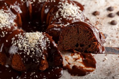 Hindistancevizi parçalı, yuvarlak çikolatalı kek yemeye hazırım. Kesici spatula ile kesilmiş bir parça servis için çıkarılıyor. Islak çikolatalı puding mermere sürülmüş gibi görünür..