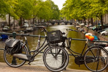 Amsterdam, Hollanda 05-15-2010: Klasik eski tarz motorlar Amsterdam 'ın ünlü kanal ağı üzerindeki köprülerden birinin metal korkuluklarına zincirlenmiştir. Bu şehirde bisiklet sürmek yaygındır..