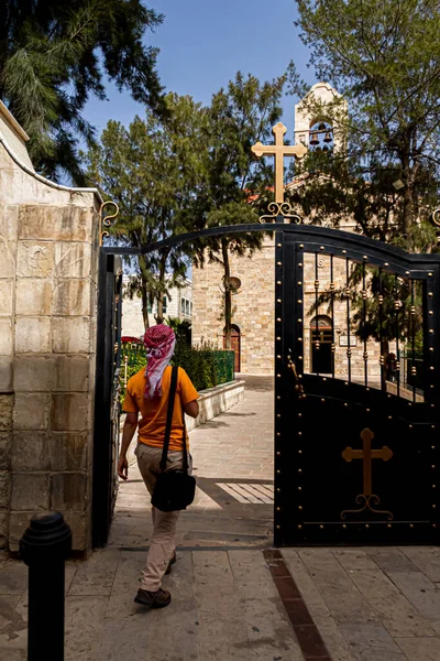 An Arabic person wearing Jordanian Keffiyeh is entering the historic Byzantine church of Saint George in Madaba, Jordan. This ancient church has the famous mosaic map of middle east.