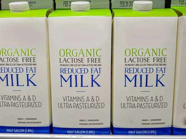 Half gallon cartons of lactose free reduced fat organic milk on fridge shelf. This is for people who are lactose intolerant due to enzymatic deficiency of lactase in adulthood.