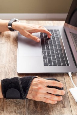 Bilgisayar faresi kullanan insanlarda bilek ekleminde kronik travma iltihaplanmaya ve ağrıya neden olan rahatsızlıklara yol açabilir. Masada çalışan bir kadın bilek desteği ve ergonomik dikey fare kullanır