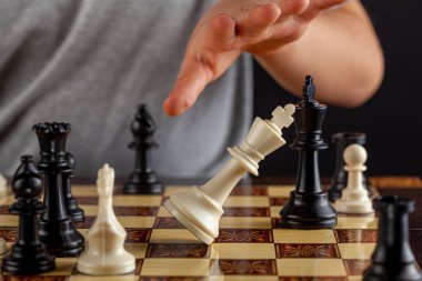 Satrancın sonunun yakın plan görüntüsü, kaybeden oyuncunun şahını devirerek istifa ettiği sahne. Görüntü, kralın düşüşünü gösteriyor. Yenilgi, başarısızlık ve istifa kavramları için çok yönlü resim.