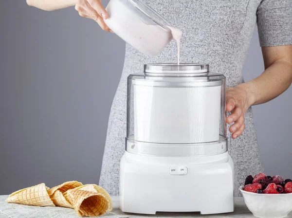 Kafkasyalı bir kadın tüm doğal dondurma karışımlarını bir dondurma makinesine döküyor. Çilek ve çilek tat katmak için eklendi. El yapımı waffle külahları hazır..
