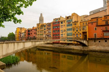 Girona, İspanya 05-01-2010: Pont d 'en Gomez o de la princesa Onyar nehri üzerindeki yaya köprüsü nehrin karşı kıyısında kırsal bir apartman bloğuna dönüşüyor. Basilica de Sant Felix Kulesi görüldü.