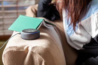 Clarksburg, MD, ABD 03-01-2021: Evinde günlük kıyafetlerle oturan beyaz bir kadın Amazon Echo Dot 'a bir soru soruyor, sesle çalışan hoparlör cihazı.