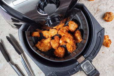 Close up flat lay image of an air fryer oven on kitchen countertop. This offers fast and easy crispy food with little or no fat by circulating hot air inside the basket. A healthy snack alternative. clipart