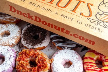 Clarksburg, MD, ABD 03-04-2021: Ördek Donutları zincirinden alınmış bir düzine donutun karton kutusu. Taze çörek siparişi vermek için popüler bir donut seçimi yapılır.