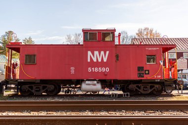 Clifton, VA, USA 11-14-2020: Manzaralı Clifton 'daki tarihi Devereux İstasyonu' nun önüne tren rayları tarafından yerleştirilmiş kırmızı bir vintage vagon. Bu propan tankı olan eski bir kırmızı metal yolcu vagonu..