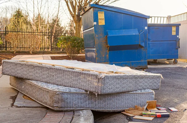 Despite regulations by the Home owners association, residents still illegally dump bulk items by the residential trash containers. Two old mattresses left behind by dumpster create unsightly look.