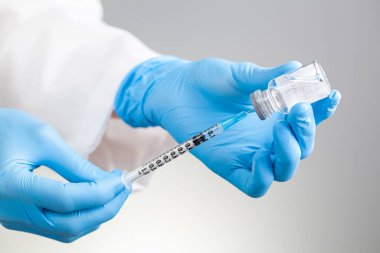 Sıvı ilaç ya da aşıyı emici kapaklı cam şişeden şırıngaya çeken bir sağlık uzmanı için izole edilmiş konsept görüntüyü kapatın. Aşı için uygun, terapi kavramları.