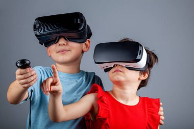 Beyaz bir erkek ve sanal gerçeklik kulaklığı takan bir kız çoklu oyuncu oyunu oynuyorlar. Çok oyunculu oyun sırasında çocukların farklı bir boyutta olduğu fütürist bir kavram. Bağımlılık etkinliği.