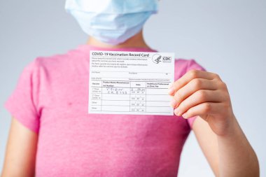 04-02-2021 Clarksburg, MD, ABD: Çocukların okul başlamadan önce aşı olmaları bekleniyor. Elinde COVID 19 aşı kartıyla gezen bir çocuğun resmi.