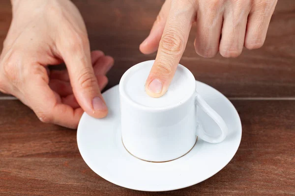 A caucasian woman is performing fortune reading ( kahve fali ) using leftover coffee grounds in ceramic Turkish coffee cup. A popular activity in Turkey. Coffee drops form shapes and patterns.