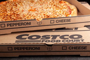 Clarksburg, MD, USA 04-7-2021: Closeup angled image of a carton box of delicious made to order COSTCO cheese pizza. Very popular bargain priced food court item from the wholesale giant.  clipart