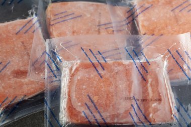 Closeup isolated image of four packs of individually packaged salmon fillets. The air tight vacuum sealed packs are frozen and the instructions say they need to be thawed in fridge. clipart