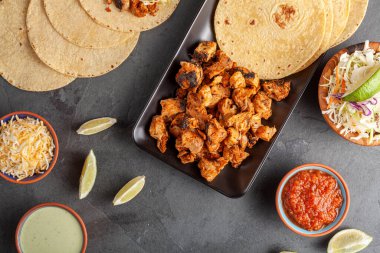 Meksika taco tabağı, mısır tortillası, önceden pişirilmiş tavuk parçaları, lahana salatası, dilimlenmiş peynir, salsa ve krem sosu ve limon dilimleri. Düz görünüm resmi yatıyordu.