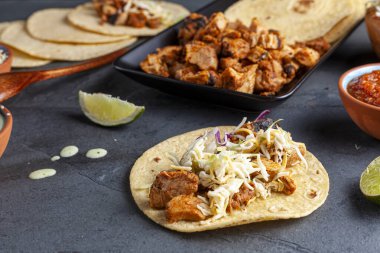 Meksika taco tabağı, mısır tortillası, önceden pişirilmiş tavuk parçaları, lahana salatası, dilimlenmiş peynir, salsa ve krem sosu ve limon dilimleri. Açılı seçici odak resmi.