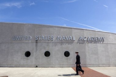 Annapolis, MD, ABD 05-02-2021: Annapolis 'teki ABD Deniz Harp Okulu binasının önünde genç bir donanma subayı adayı yürüyor. Öğrenci üniforma giyiyor, COVID-19 salgınından dolayı maske takıyor.