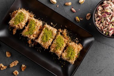 Türk Tel Kaday, cevizle karıştırılmış doğranmış fillo hamurundan yapılmış tatlı. Kalın şurupla tatlandırılır ve dekorasyon ve lezzet için üstüne fıstık ezmesi eklenir. İçinde malzeme olan bir tabak.