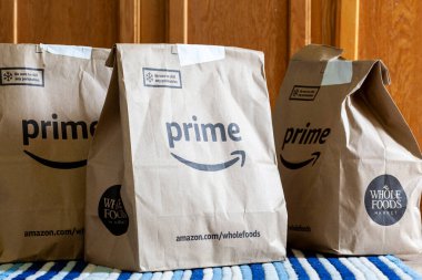 Clarksburg, MD, ABD 05-12-2021: Amazon Prime ve Whole Foods süpermarket logolarına sahip geri dönüştürülmüş üç poşet. Amazon, tüm bakkal ürünlerinin ana üyelerine aynı gün ücretsiz teslimatı sunar..