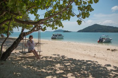 İp salıncağa sahilde oturan genç güzellik kadın