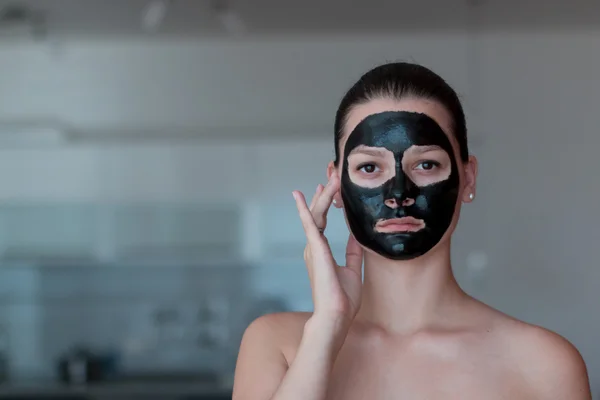 Young beautiful woman with a black mask for the face — Stock Photo, Image